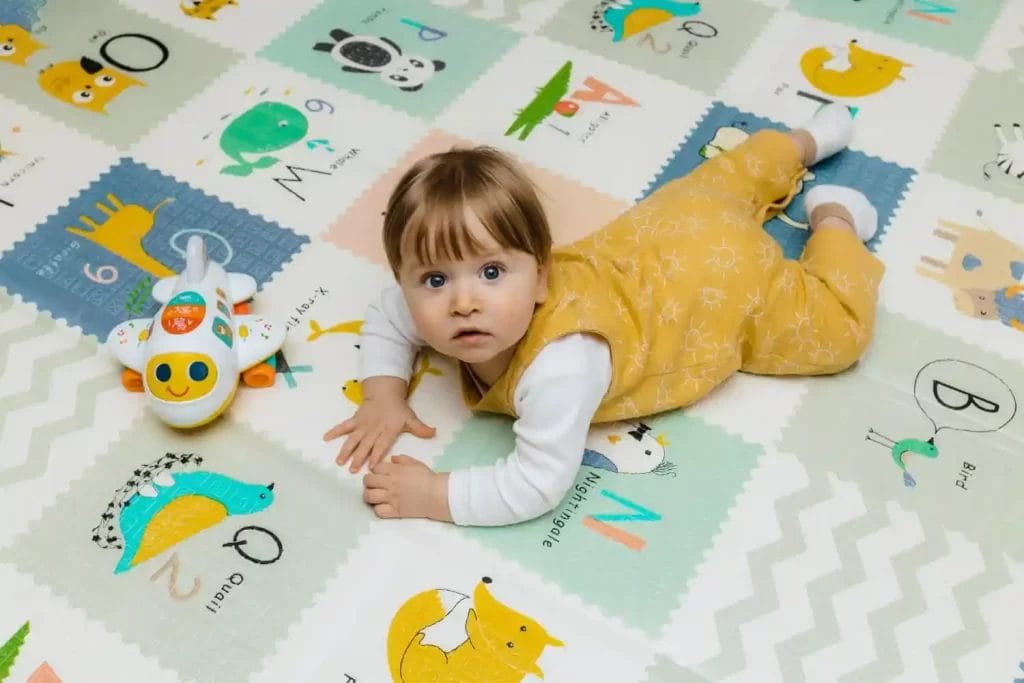 bayi berbaring di atas playmat bayi