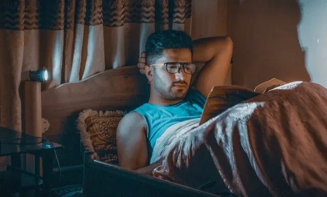 pria membaca buku di kasur