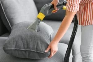 wanita membersihkan bantal dengan vacuum cleaner