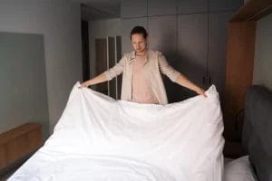 pria membereskan tempat tidur