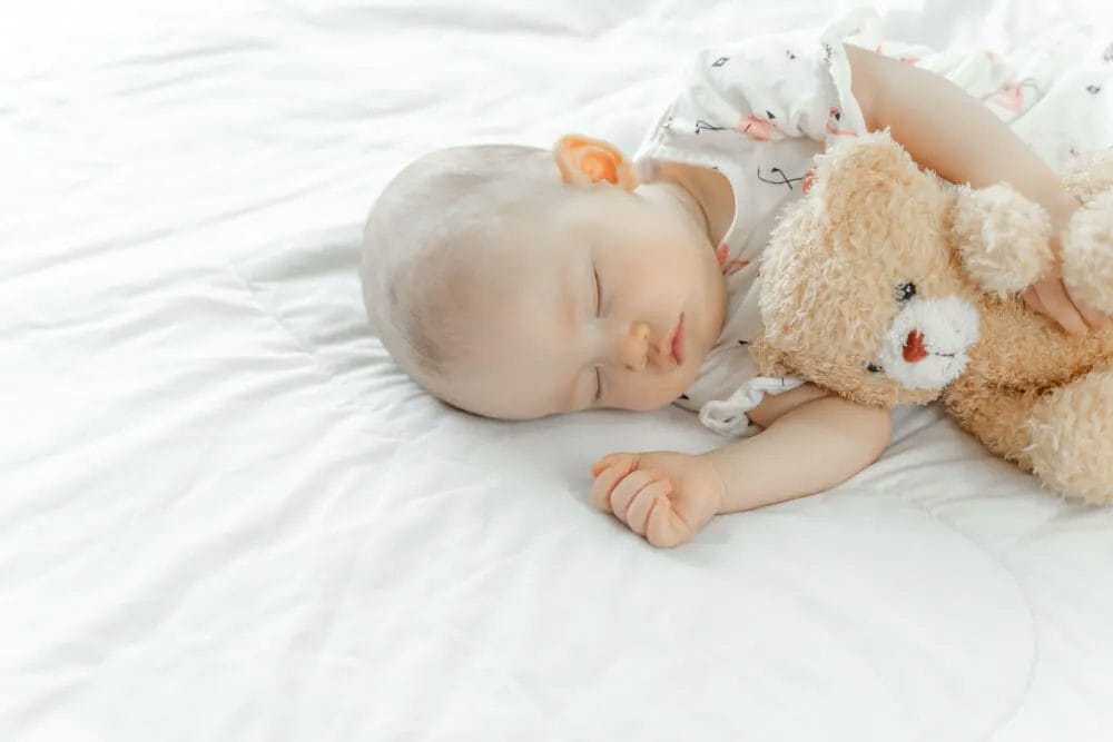 bayi tidur dengan boneka beruang