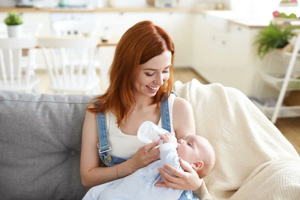 wanita memberikan susu botol ke bayi